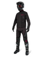Alpinestars Lite-Dura Softshell Jacket, nero, indossata da un manichino come parte di un completo da fuoristrada, pantaloni neri, stivali neri e bianchi, casco nero con occhiali rossi, abbigliamento professionale da motocross ed enduro.