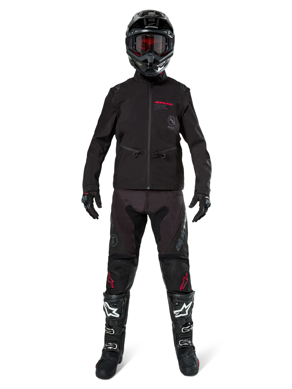 Pilota di motocross con Giacca Softshell Alpinestars Lite-Dura in nero e dettagli del logo rossi, abbinata a pantaloni off-road neri coordinati, casco nero e stivali bianchi e neri, abbigliamento professionale completo da enduro