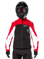 Giacca Softshell Alpinestars Lite-Dura in nero, rosso acceso e bianco, indossata da un pilota di motocross con casco nero e maschera con lenti rosse, con pannelli bianchi sulle maniche, logo Alpinestars sul petto e un design sportivo da fuoristrada.