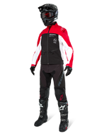 Pilota di motocross con Giacca Softshell Alpinestars Lite-Dura in nero, rosso brillante e bianco, caratterizzata da corpo nero e maniche rosse e bianche, abbinata a pantaloni neri, casco nero con occhiali rossi e stivali neri e bianchi, completo da corsa fuoristrada