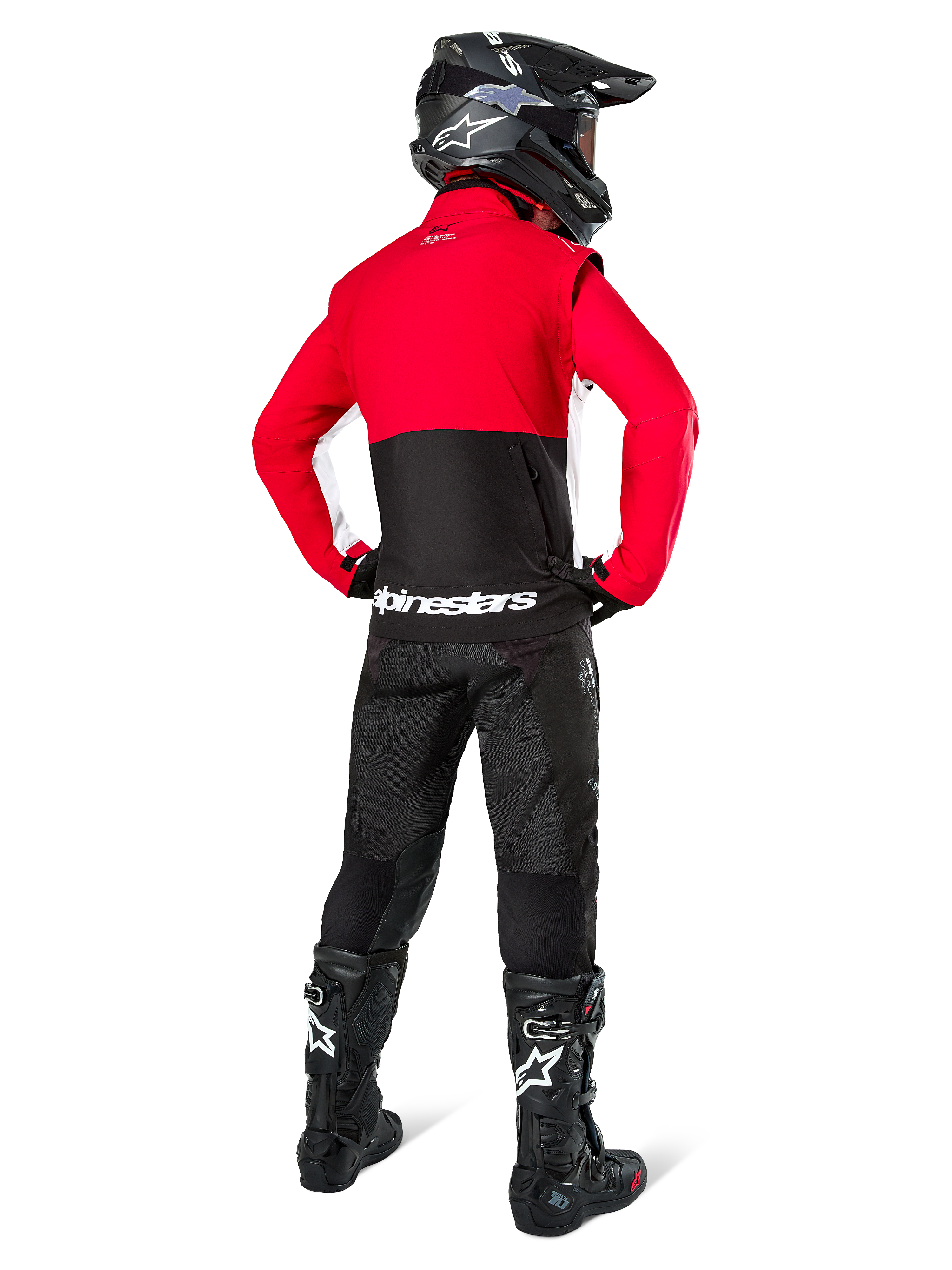Pilota di motocross da dietro con giacca Softshell Alpinestars Lite-Dura, nero rosso acceso e bianco, con pannello superiore rosso e sezione inferiore nera con branding bianco, abbinata a pantaloni neri, casco nero e stivali neri, completo da enduro coordinato per guida off-road