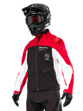 Giacca Softshell Alpinestars Lite-Dura, giacca da moto, nero, rosso acceso e bianco, indossata da un pilota con casco da motocross nero, occhiali rossi e guanti, con logo evidente sul petto, progettata per la guida off-road ed enduro