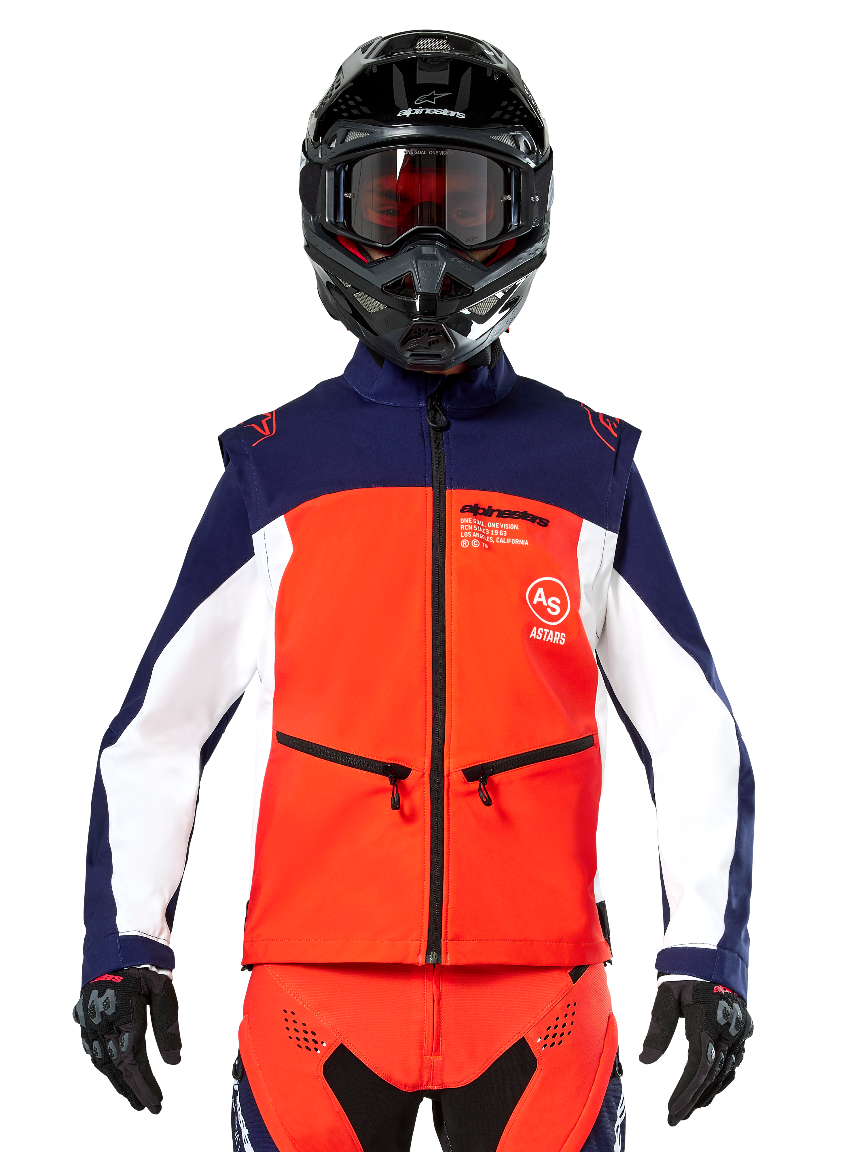 Giacca Softshell Alpinestars Lite-Dura in blu navy, arancione acceso e bianco, vista frontale su un pilota con casco nero e maschera, design tecnico color-block con tasche con zip e logo Alpinestars, attrezzatura versatile per enduro e fuoristrada