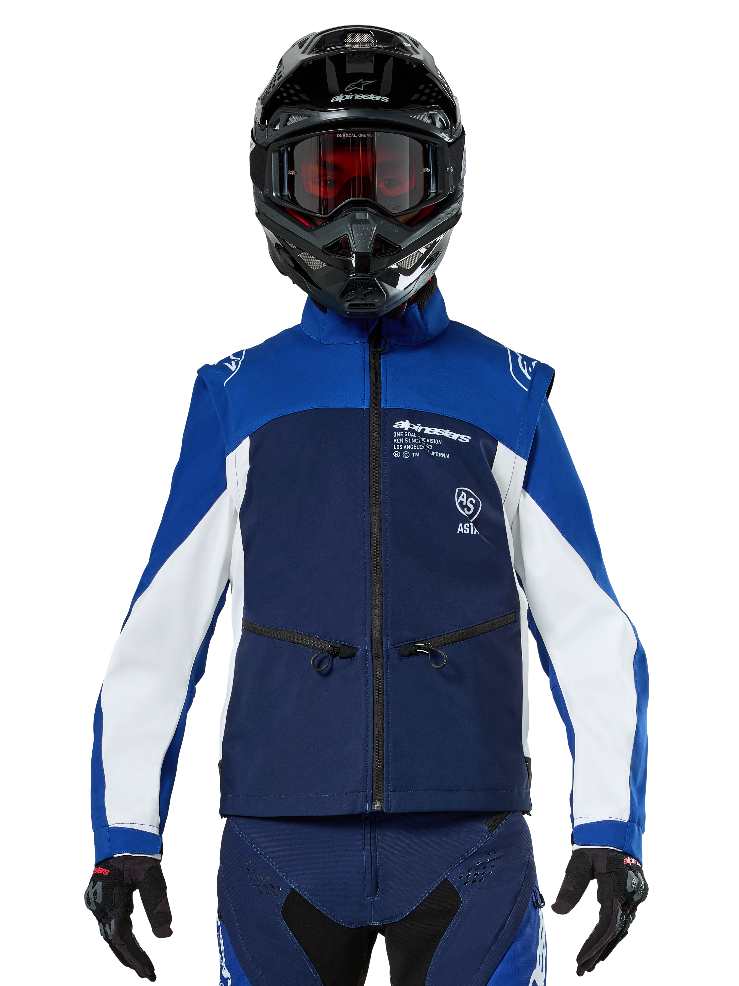 Pilota di motocross che indossa la Giacca Softshell Alpinestars Lite-Dura in Navy Bright Blue White, vista frontale, abbinata a un casco nero e una maschera con lenti rosse, caratterizzata da un design tecnico antivento con tasche con zip e dettagli bianchi per la guida enduro fuoristrada