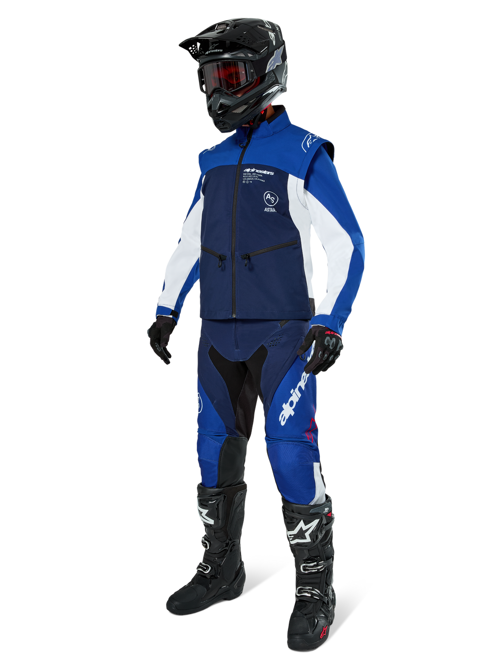 Giacca Softshell Alpinestars Lite-Dura, blu navy, azzurro e bianco, indossata con pantaloni da fuoristrada coordinati, stivali da motocross neri, casco nero con occhiali e guanti neri, equipaggiamento completo da enduro per gare fuoristrada