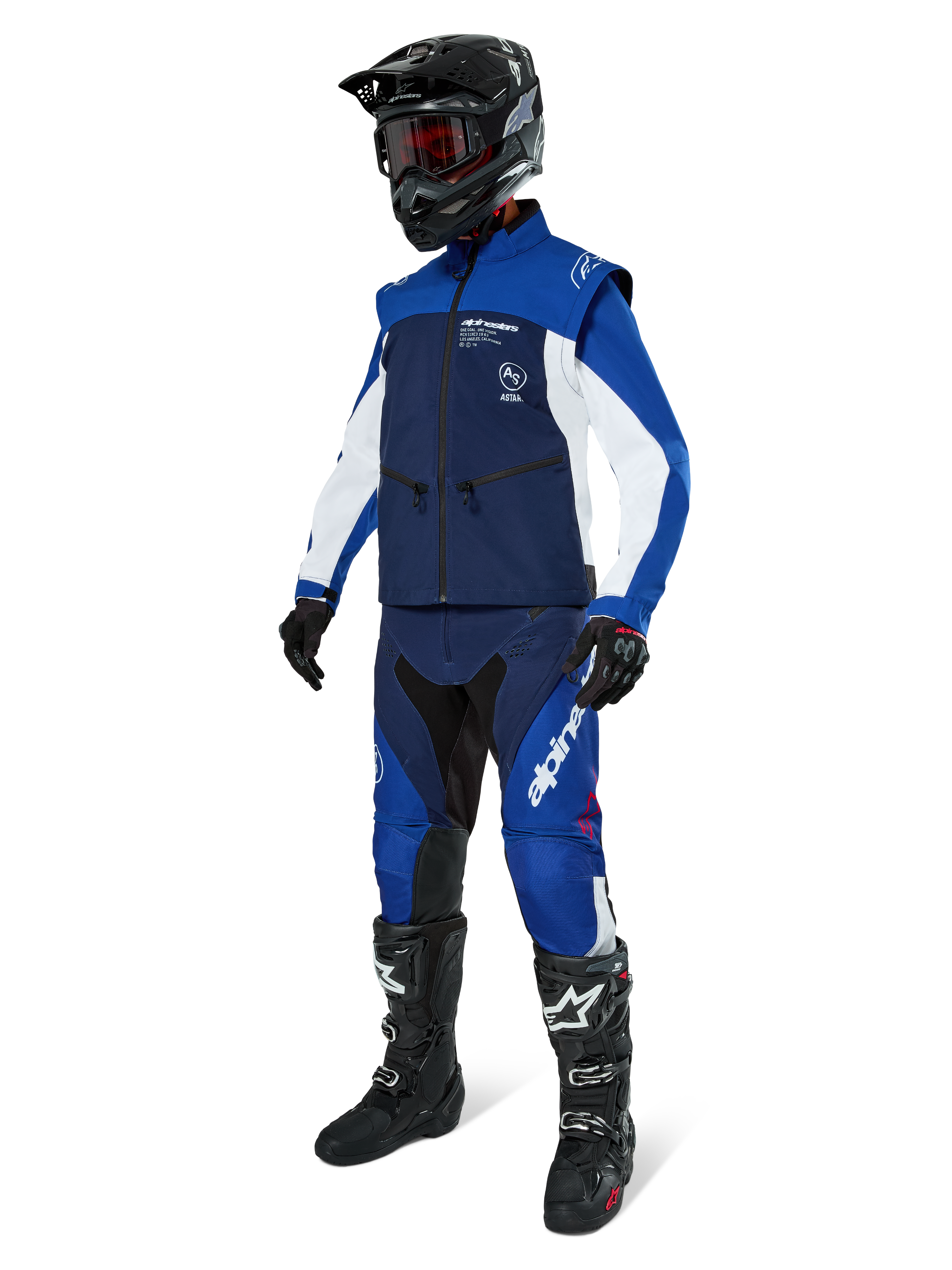 Giacca Softshell Alpinestars Lite-Dura, blu navy, azzurro e bianco, indossata con pantaloni da fuoristrada coordinati, stivali da motocross neri, casco nero con occhiali e guanti neri, equipaggiamento completo da enduro per gare fuoristrada