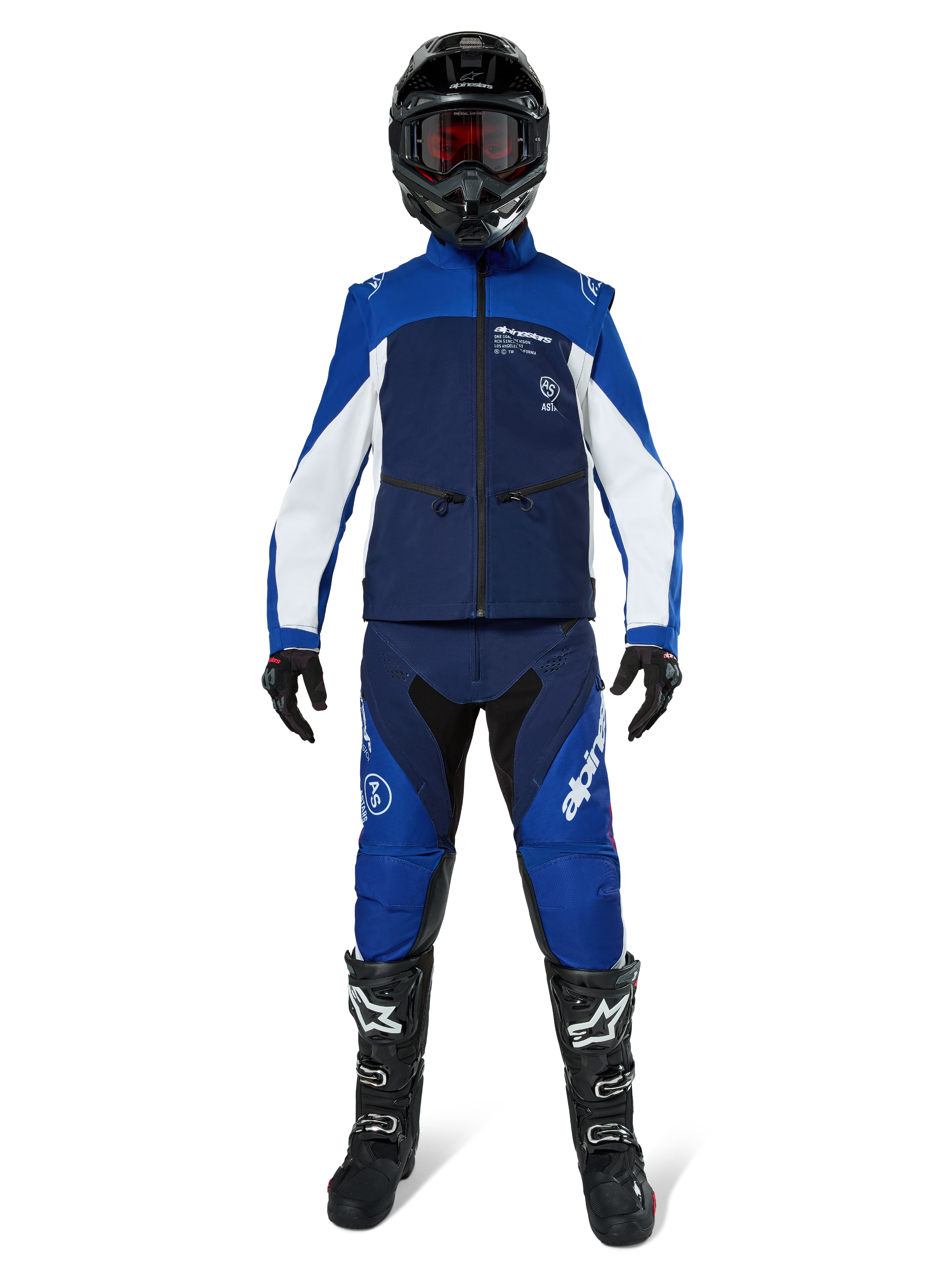 Giacca Softshell Alpinestars Lite-Dura, giacca da moto off-road in blu navy, azzurro e bianco, indossata con un set completo coordinato comprensivo di casco nero, pantaloni da enduro e stivali neri, abbigliamento tecnico antivento per guida fuoristrada