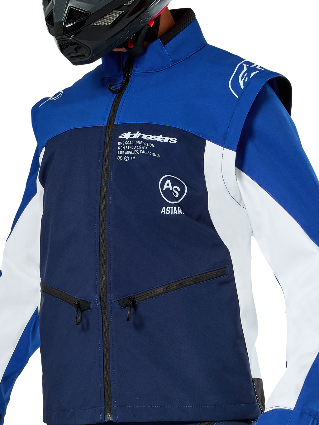 Giacca Softshell Alpinestars Lite-Dura, giacca da motocross ed enduro, blu navy, blu brillante e bianco, con logo Alpinestars bianco sul petto e tasche con zip, indossata con casco nero, struttura in softshell resistente con maniche staccabili per la guida off-road.