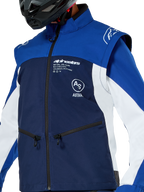 Giacca Softshell Alpinestars Lite-Dura, giacca da motocross ed enduro, blu navy, blu brillante e bianco, con logo Alpinestars bianco sul petto e tasche con zip, indossata con casco nero, struttura in softshell resistente con maniche staccabili per la guida off-road.