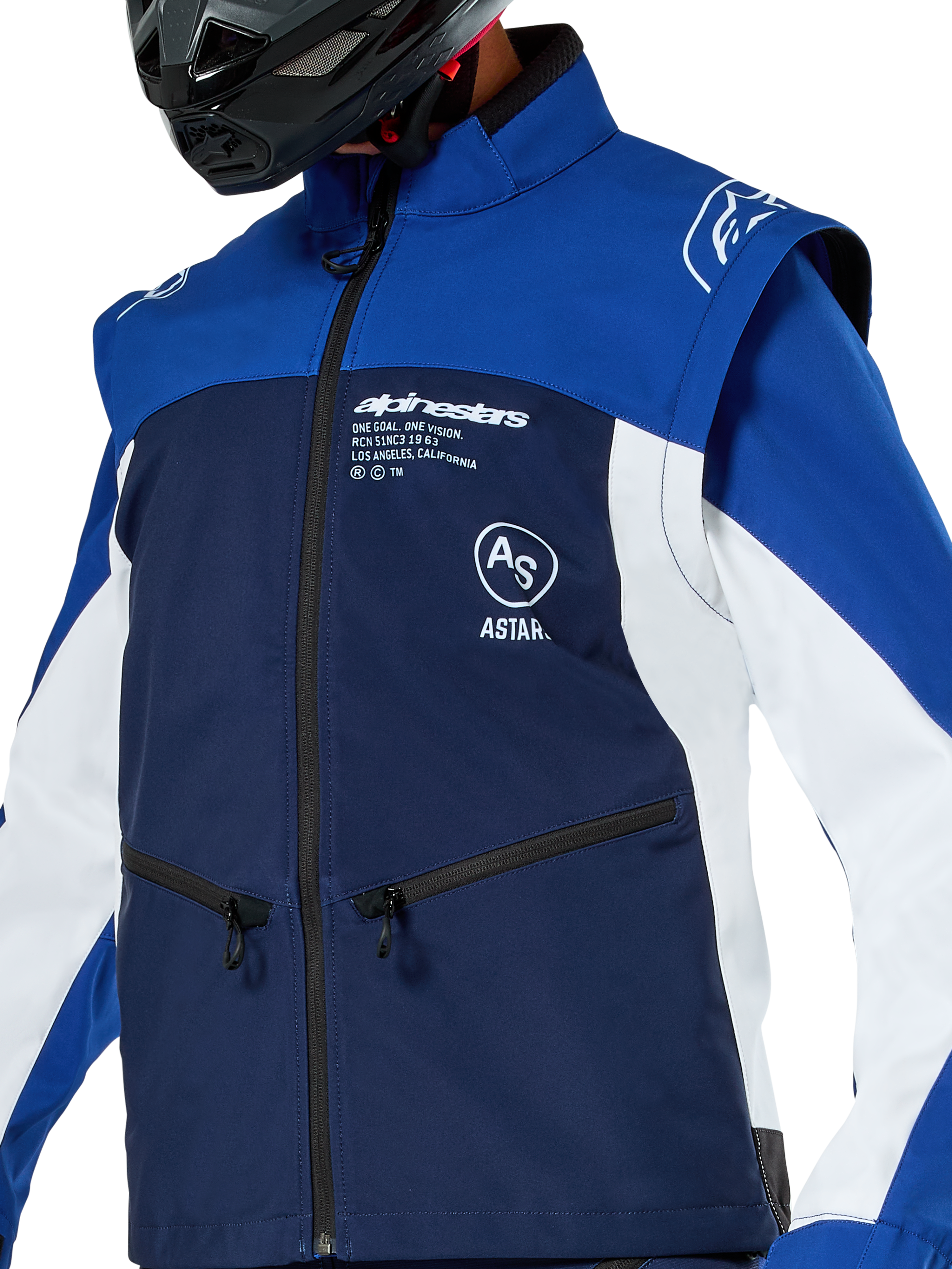 Giacca Softshell Alpinestars Lite-Dura, giacca da motocross ed enduro, blu navy, blu brillante e bianco, con logo Alpinestars bianco sul petto e tasche con zip, indossata con casco nero, struttura in softshell resistente con maniche staccabili per la guida off-road.
