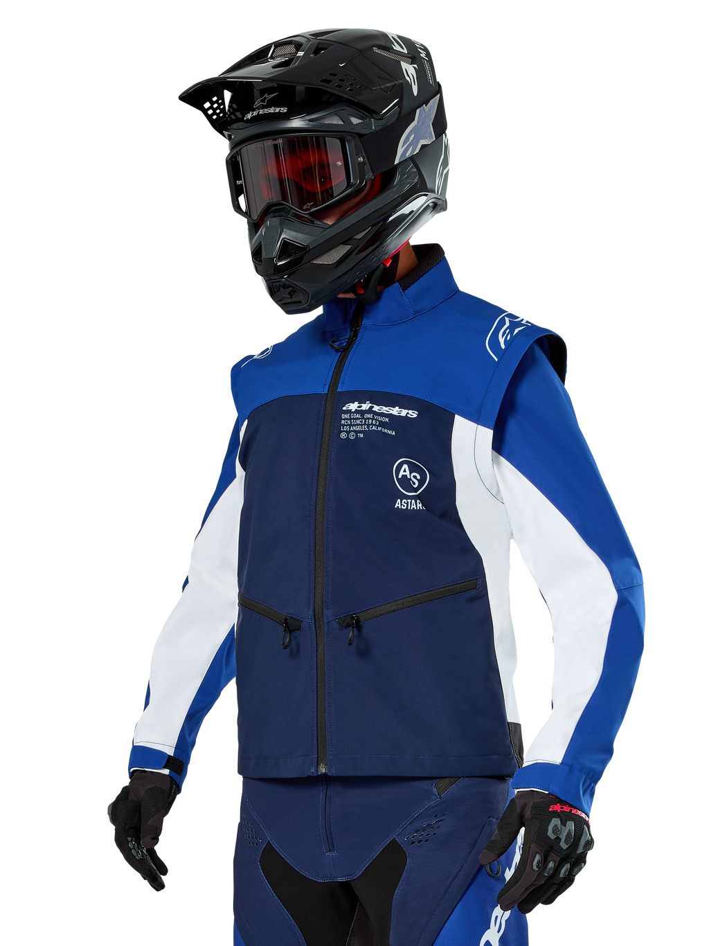 Giacca Softshell Alpinestars Lite-Dura, blu navy, azzurro e bianco, giacca da enduro off-road, indossata con casco nero e occhiali con lenti rosse, design sportivo color-block con cerniere multiple e loghi del brand, tessuto resistente per motocross e trail riding