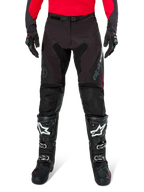 Pantaloni Alpinestars Pro-Dura, pantaloni da enduro neri e magnet, indossati con una maglia rossa a maniche lunghe e stivali da motocross neri, caratterizzati dal marchio Alpinestars grigio e dalla robusta costruzione in ripstop per la guida fuori strada