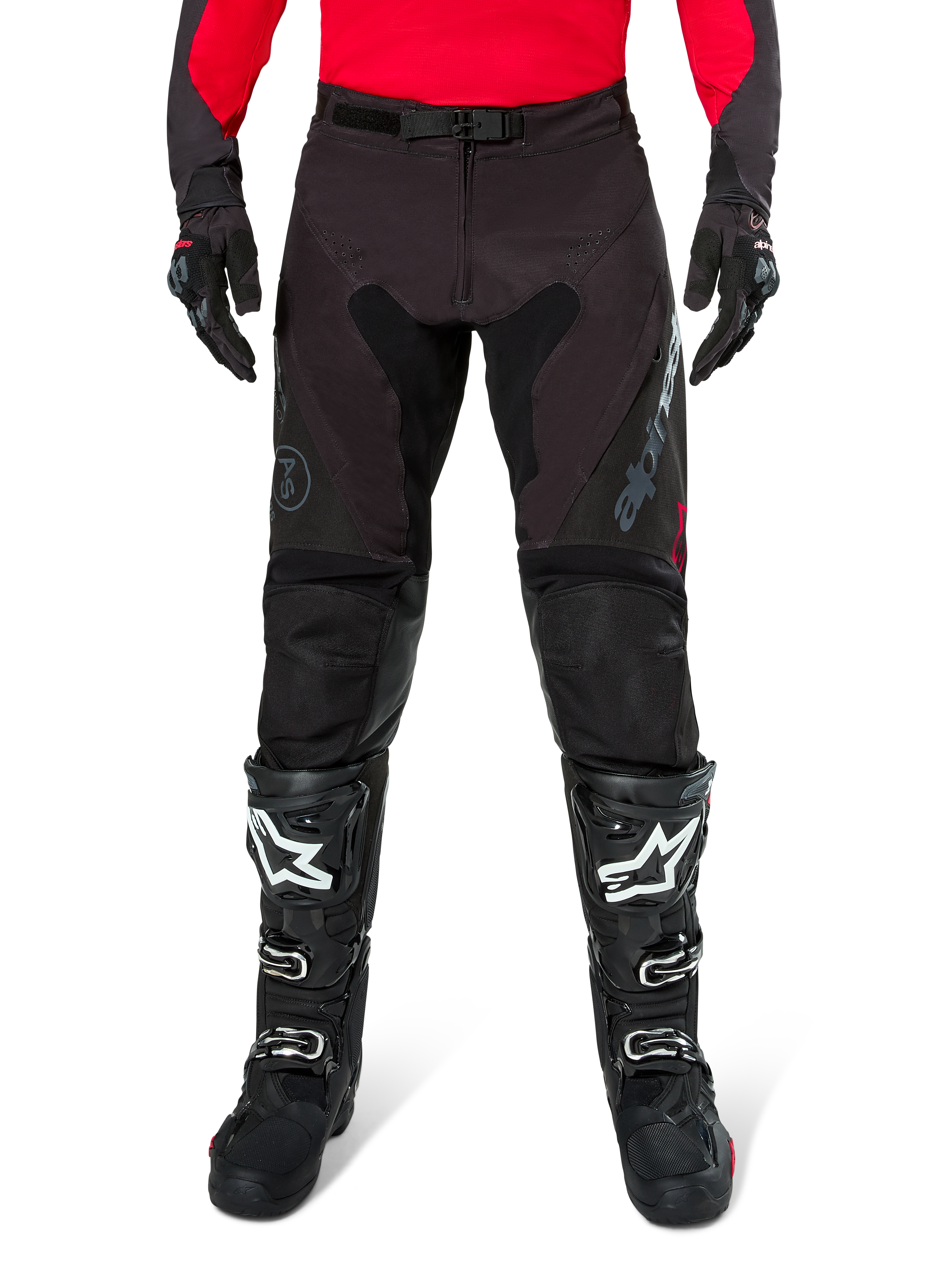 Pantaloni Alpinestars Pro-Dura, pantaloni da enduro neri e magnet, indossati con una maglia rossa a maniche lunghe e stivali da motocross neri, caratterizzati dal marchio Alpinestars grigio e dalla robusta costruzione in ripstop per la guida fuori strada