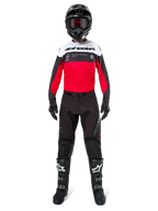 Pilota di motocross con pantaloni Alpinestars Pro-Dura in nero e magnet, maglia rossa, bianca e nera, casco nero e stivali neri, kit completo da gara off-road, design resistente e leggero per enduro