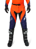 Pantaloni Alpinestars Pro-Dura, pantaloni da motocross ed enduro, blu navy, arancione acceso e bianco, con pannelli neri e loghi bianchi, indossati con stivali e guanti da fuoristrada neri, abbigliamento protettivo professionale per trail e off-road