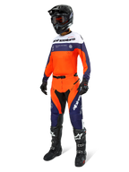 Pantaloni Alpinestars Pro-Dura, pantaloni da motocross ed enduro, blu navy, arancione acceso e bianco, indossati come parte di un set completo da gara con maglia coordinata, casco nero e stivali neri, caratterizzati da pannelli resistenti e branding audace per prestazioni off-road.