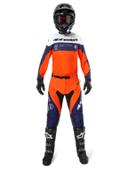 Pilota di motocross con pantaloni Alpinestars Pro-Dura in Blu Navy, Arancione Hot e Bianco, maglia a maniche lunghe coordinata, casco nero con occhiali, guanti neri e stivali da motocross neri, equipaggiamento completo per fuoristrada