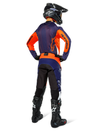 Pilota di motocross con abbigliamento da gara completo visto di spalle, maglia blu navy e arancione, pantaloni Pro-Dura in Navy Hot Orange White, casco e stivali neri, completo professionale da corsa off-road.
