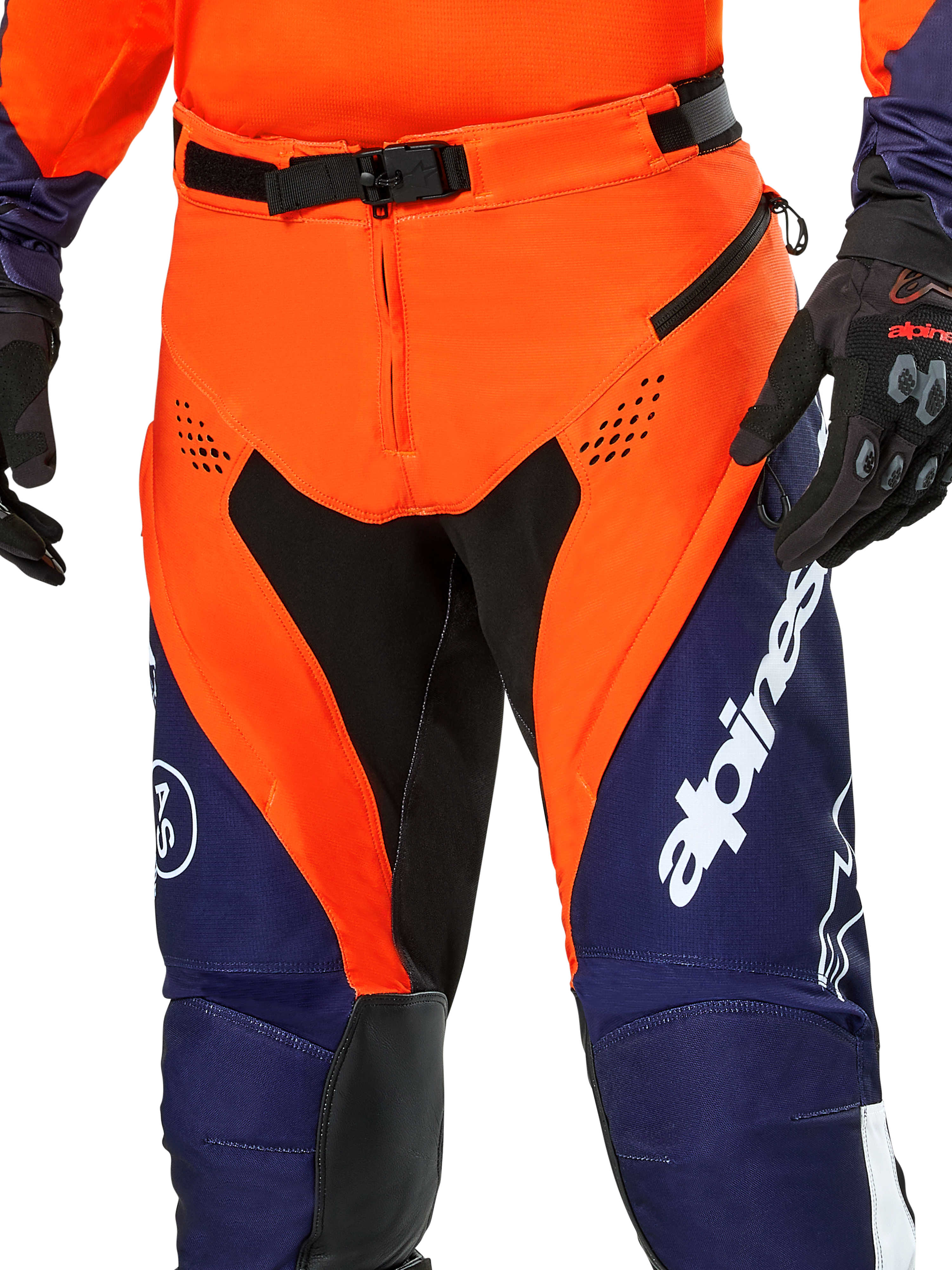 Alpinestars Pro-Dura Pants, pantaloni da moto enduro, blu navy, arancione acceso e bianco, vista del dettaglio della vita con fibbia magnetica SX2 e prese d'aria con zip sulle cosce, materiale ripstop resistente con branding evidente, indossati con abbigliamento coordinato