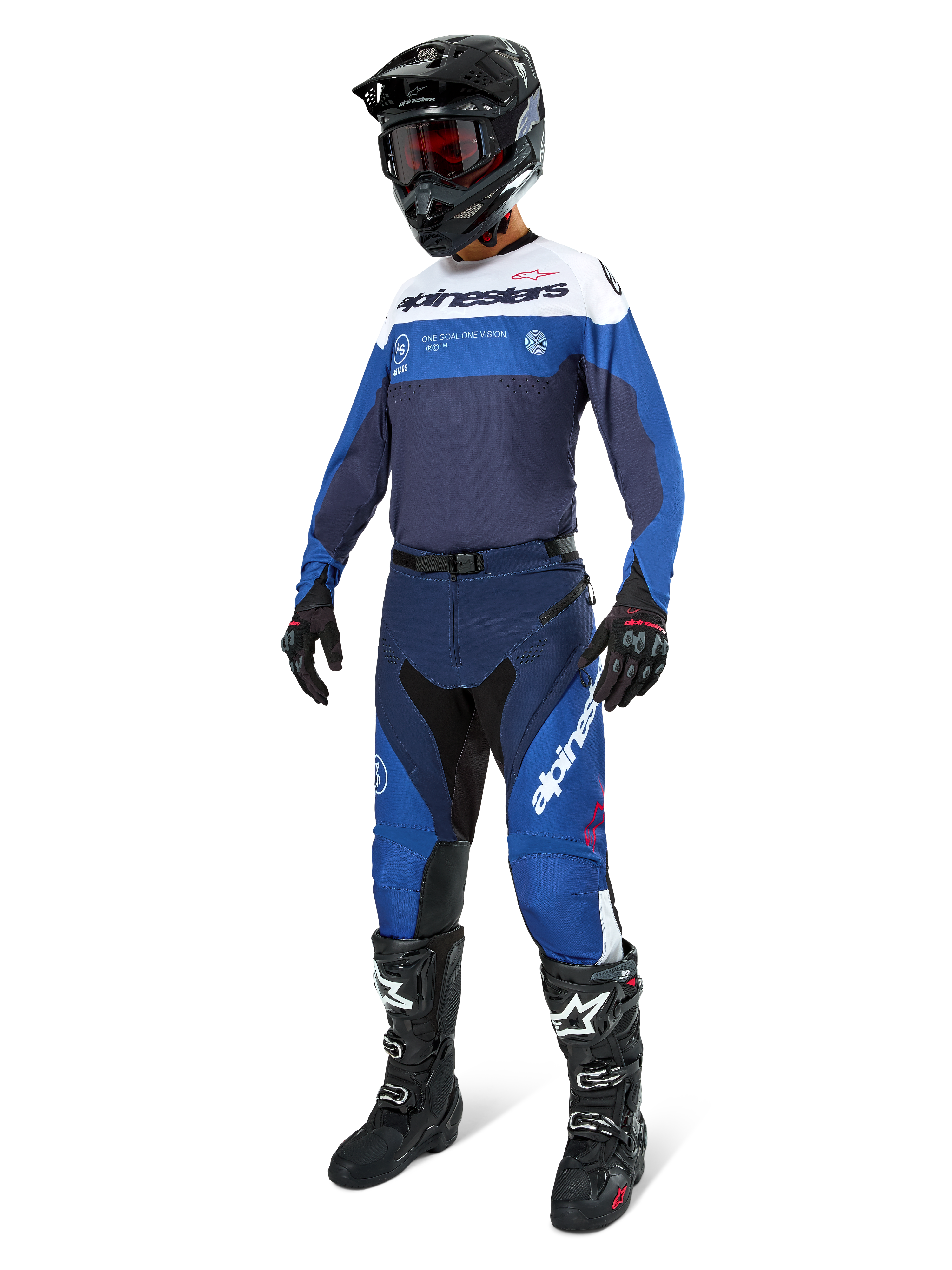 Pilota di motocross che indossa pantaloni Alpinestars Pro-Dura in Blu Navy, Blu Brillante e Bianco, abbinati a una maglia a maniche lunghe coordinata, casco nero con occhiali rossi, guanti neri e stivali bianchi e neri, completo coordinato per enduro e gare fuoristrada.