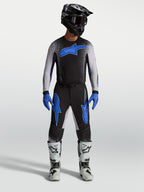 Alpinestars pantaloni Supertech Hiten AFD, pantaloni da motocross da uomo neri e blu, indossati con maglia coordinata e stivali da corsa bianchi per fuoristrada pro racing