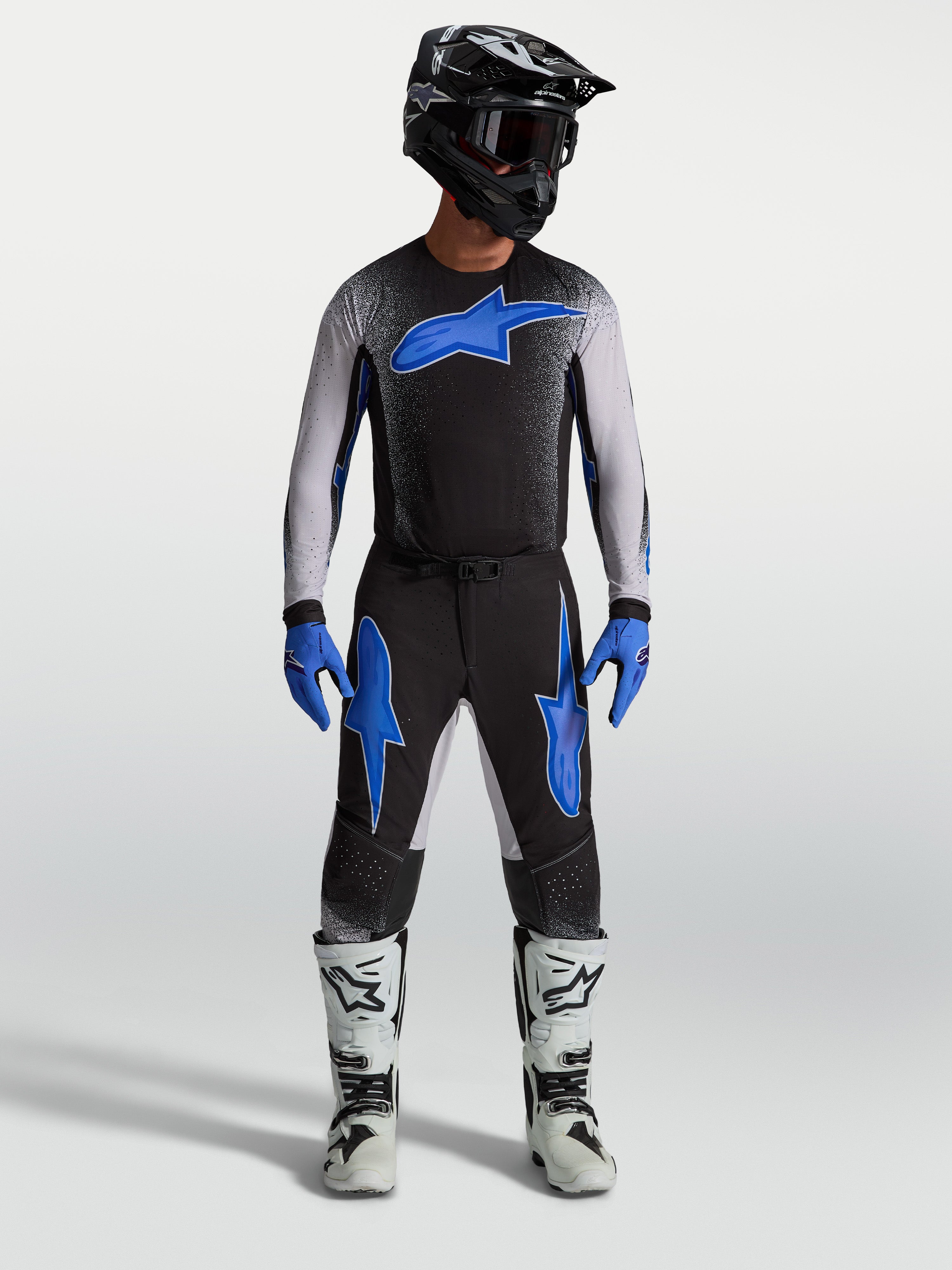 Alpinestars pantaloni Supertech Hiten AFD, pantaloni da motocross da uomo neri e blu, indossati con maglia coordinata e stivali da corsa bianchi per fuoristrada pro racing