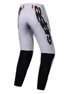 Alpinestars 2025 Supertech Maker Pants, pantaloni da motocross, argento e nero, vista posteriore con grande marchio Alpinestars nero sul lato, pannelli neri sulla parte inferiore della gamba e piccoli loghi a stella rossi sulla fascia in vita, progettati per prestazioni professionali fuoristrada