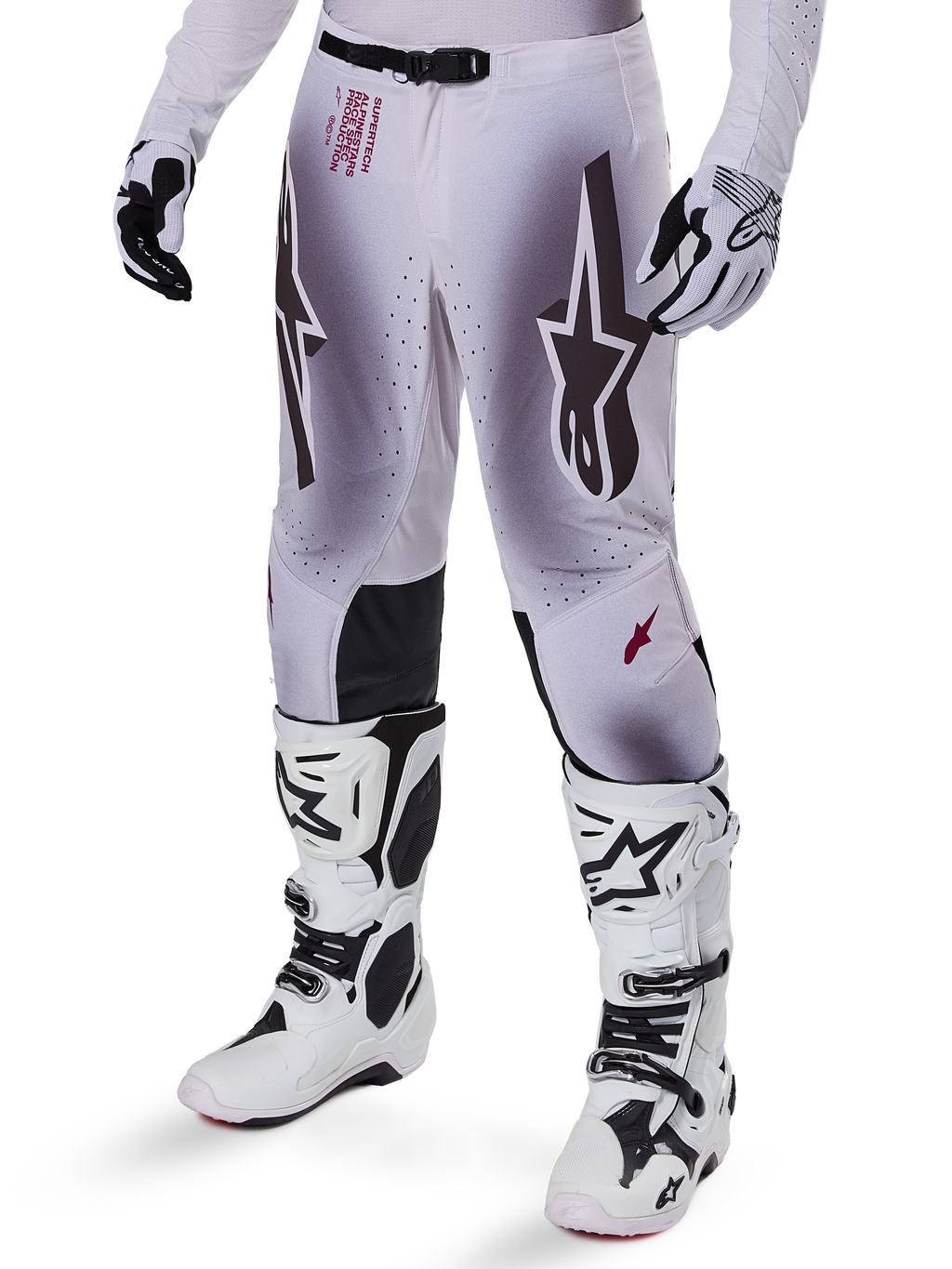 Alpinestars 2025 Supertech Maker Pants, pantaloni da motocross, argento e nero, con grandi loghi a stella e scritte rosse, mostrati con stivali e guanti bianchi coordinati