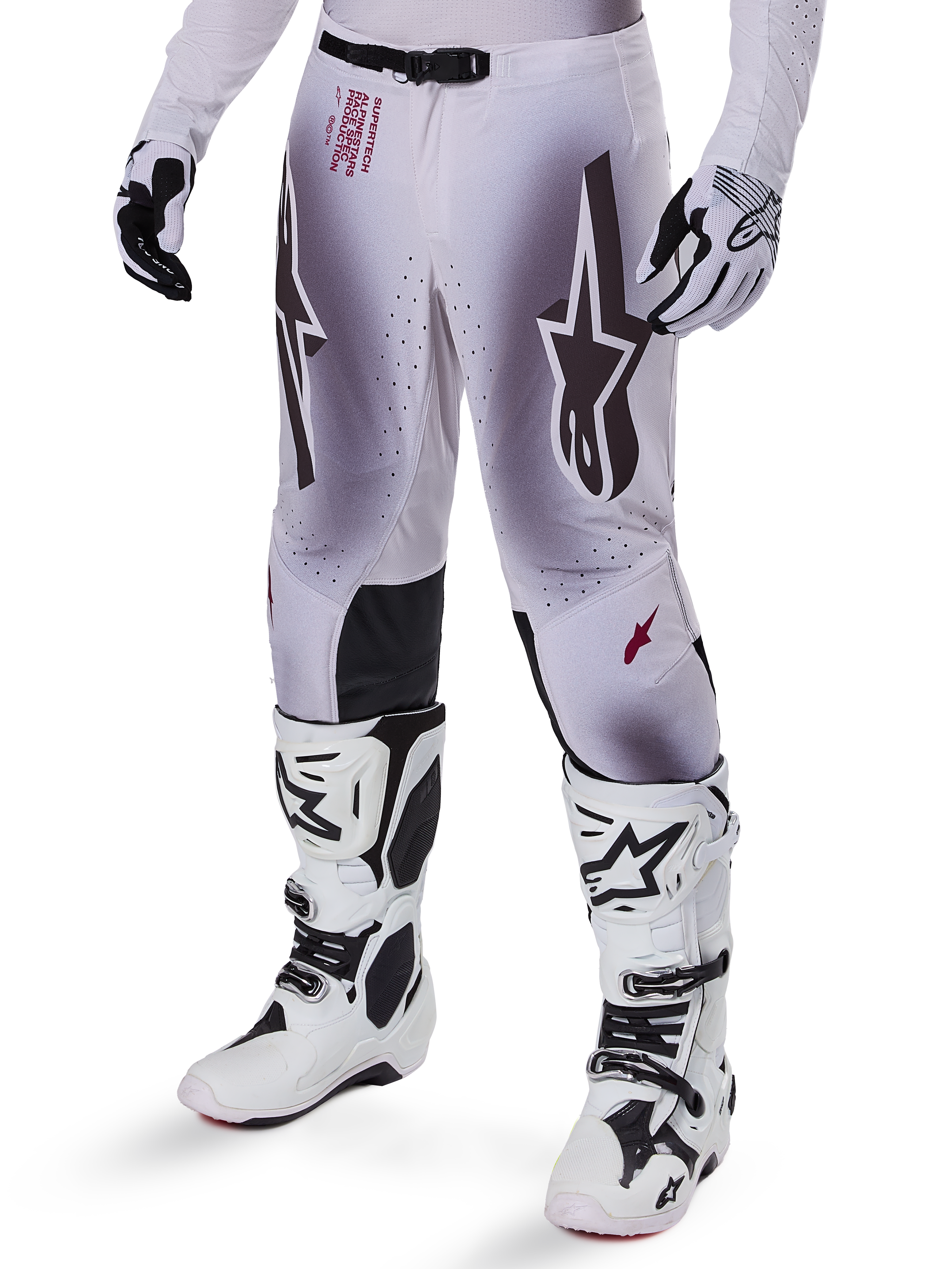 Alpinestars 2025 Supertech Maker Pants, pantaloni da motocross, argento e nero, con grandi loghi a stella e scritte rosse, mostrati con stivali e guanti bianchi coordinati