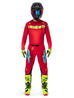 Pilota di motocross con abbigliamento completo da gara, maglia rossa con logo astars giallo fluo, pantaloni Alpinestars 2025 Supertech Maker in Rosso Brillante e Giallo Fluo con loghi blu sulle cosce, guanti e stivali giallo fluo, casco nero con occhiali blu, outfit coordinato da motocross professionale.