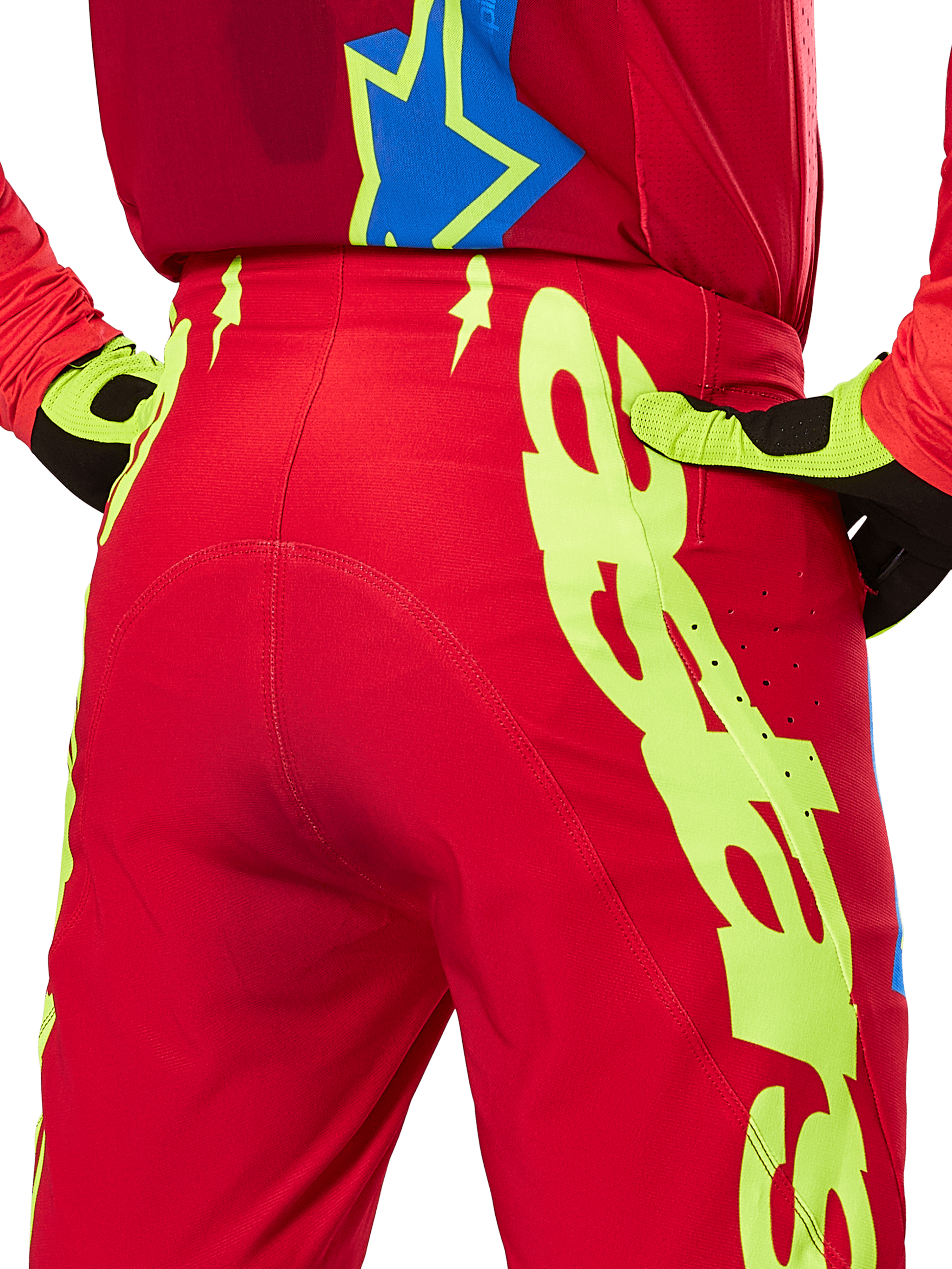 Alpinestars Pantaloni Supertech Maker 2025, pantaloni da motocross, rosso acceso e giallo fluo, primo piano posteriore con grafica giallo neon, indossati con maglia rossa coordinata e guanti gialli e neri
