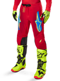Alpinestars Pantaloni Supertech Maker 2025, pantaloni da motocross, rosso acceso con loghi a stella blu e gialli, pannelli neri sulle ginocchia, ventilazione traforata, coordinati con stivali e guanti giallo neon
