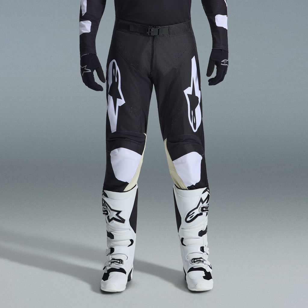 Alpinestars 2026 Racer Air Riway Gear Set, pantaloni da motocross neri e bianchi con pannelli interni alle ginocchia beige, abbinati a stivali da corsa bianchi e guanti neri, abbigliamento da corsa off-road leggero e ventilato