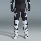 Alpinestars 2026 Racer Air Riway Gear Set, pantaloni da motocross neri e bianchi con pannelli interni alle ginocchia beige, abbinati a stivali da corsa bianchi e guanti neri, abbigliamento da corsa off-road leggero e ventilato