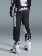 Alpinestars 2026 Racer Air Riway Pants, pantaloni da motocross, bianco e nero, vista posteriore con grande marchio Astars bianco sulla seduta e sulle gambe, pannelli interni del ginocchio in pelle tan, indossati con stivali Tech 7 bianchi e neri, abbigliamento premium per corse fuoristrada