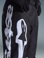 Pantaloni Alpinestars 2026 Racer Air Riway, pantaloni da motocross, nero e bianco, vista ravvicinata con grande logo Alpinestars bianco, perforazioni laser per la ventilazione e fibbia regolabile in vita, tessuto resistente per la guida fuoristrada