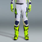 Alpinestars 2026 Racer Air Riway Gear Set, pantaloni da motocross in bianco e blu navy con accenti giallo neon, abbinati a guanti e stivali giallo neon coordinati, caratterizzati da design ergonomico e pannelli ventilati per corse off-road.