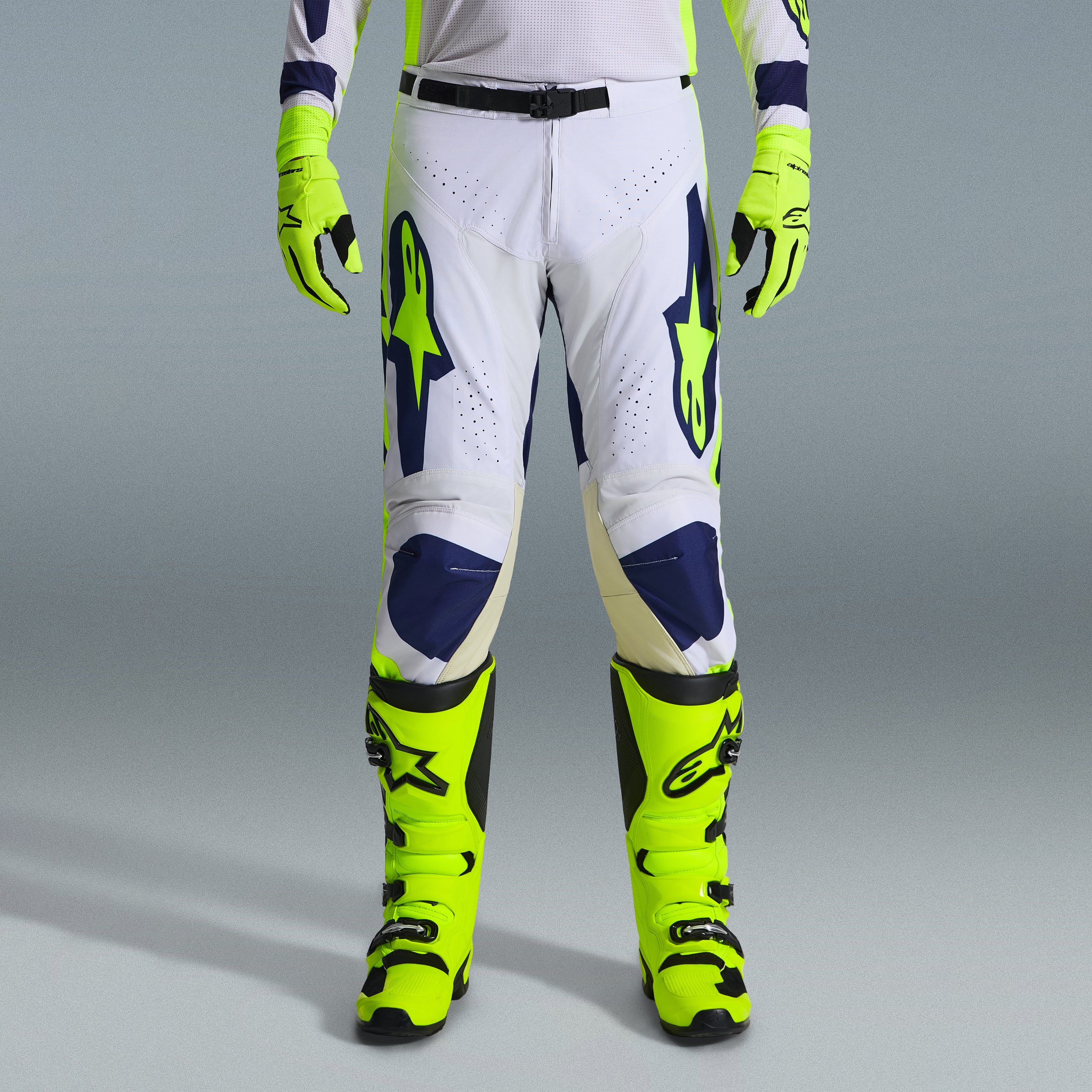 Alpinestars 2026 Racer Air Riway Gear Set, pantaloni da motocross in bianco e blu navy con accenti giallo neon, abbinati a guanti e stivali giallo neon coordinati, caratterizzati da design ergonomico e pannelli ventilati per corse off-road.