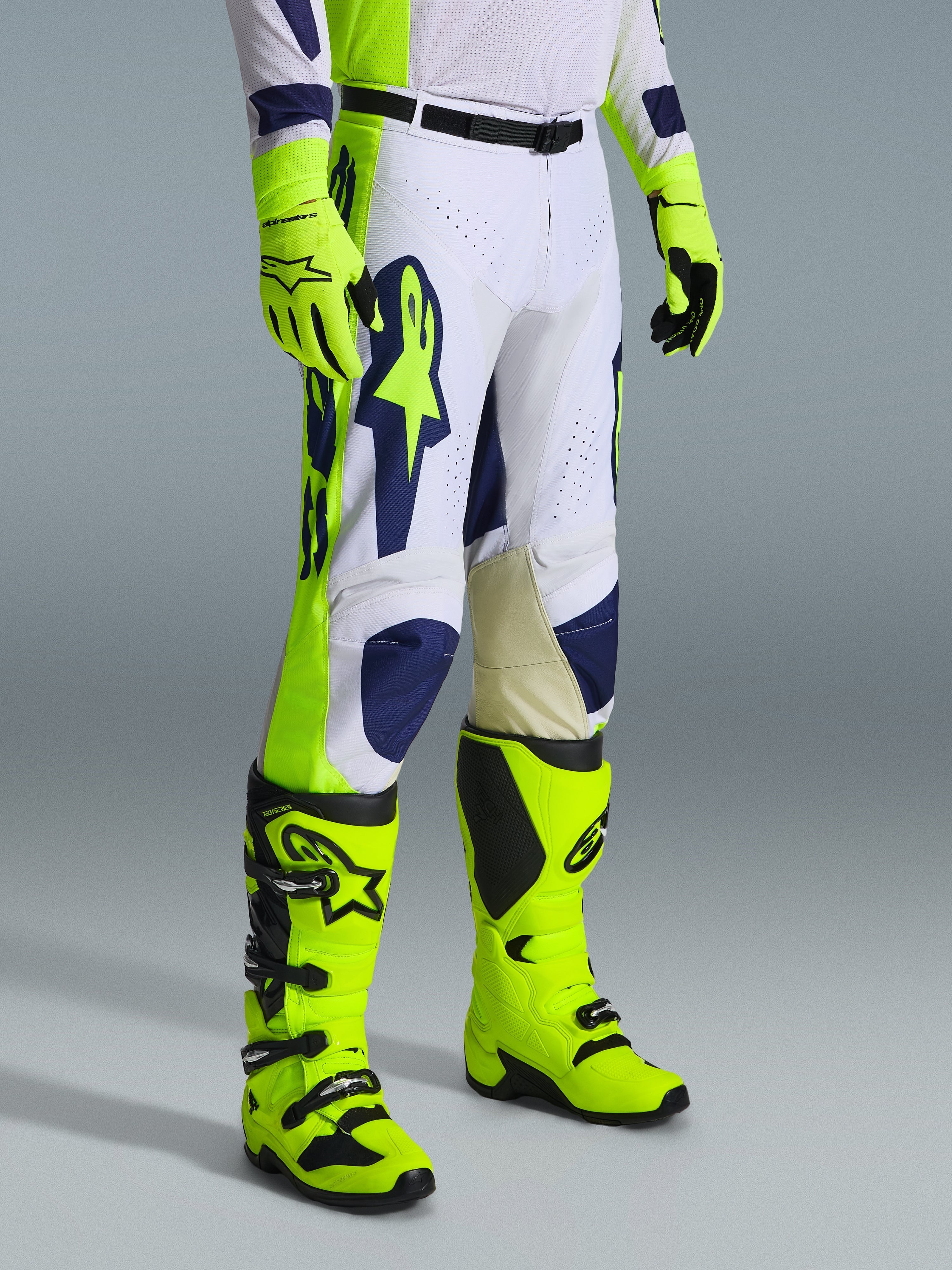 Alpinestars 2026 Racer Air Riway Gear Set, pantaloni da motocross bianchi con accenti blu navy e giallo fluo, abbinati a stivali e guanti coordinati giallo fluo, caratterizzati da traforature per il flusso d'aria e design ergonomico, completo professionale da gara off-road.