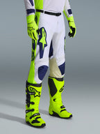 Alpinestars 2026 Racer Air Riway Pants, pantaloni da motocross, grigio chiaro, giallo fluo e blu, indossati con guanti e stivali giallo fluo coordinati, con grande marchio blu sulla coscia e pannelli di ventilazione traforati, abbigliamento resistente per motocross