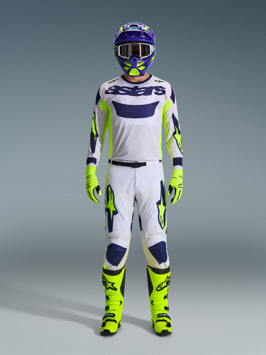 Pantaloni Alpinestars 2026 Racer Air Riway, pantaloni da motocross, grigio chiaro con giallo fluo e blu, indossati da un pilota in un set da gara completo con maglia bianca abbinata, stivali e guanti giallo fluo e casco blu, abbigliamento professionale per fuoristrada