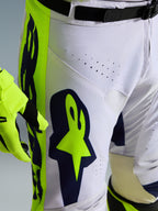 Alpinestars 2026 Racer Air Riway Pants, pantaloni da motocross, grigio chiaro con accenti giallo fluo e blu, primo piano della coscia con grande logo Alpinestars e perforazioni per la ventilazione, costruzione resistente con vestibilità da gara