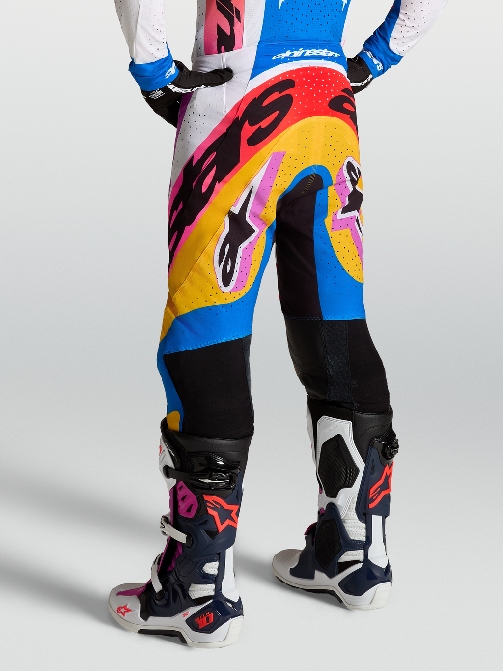 Alpinestars Pantaloni Supertech Dyna, pantaloni da motocross professionali, bianchi e blu con inserti multicolore, ventilati e leggeri, indossati con stivali Tech 10 coordinate
