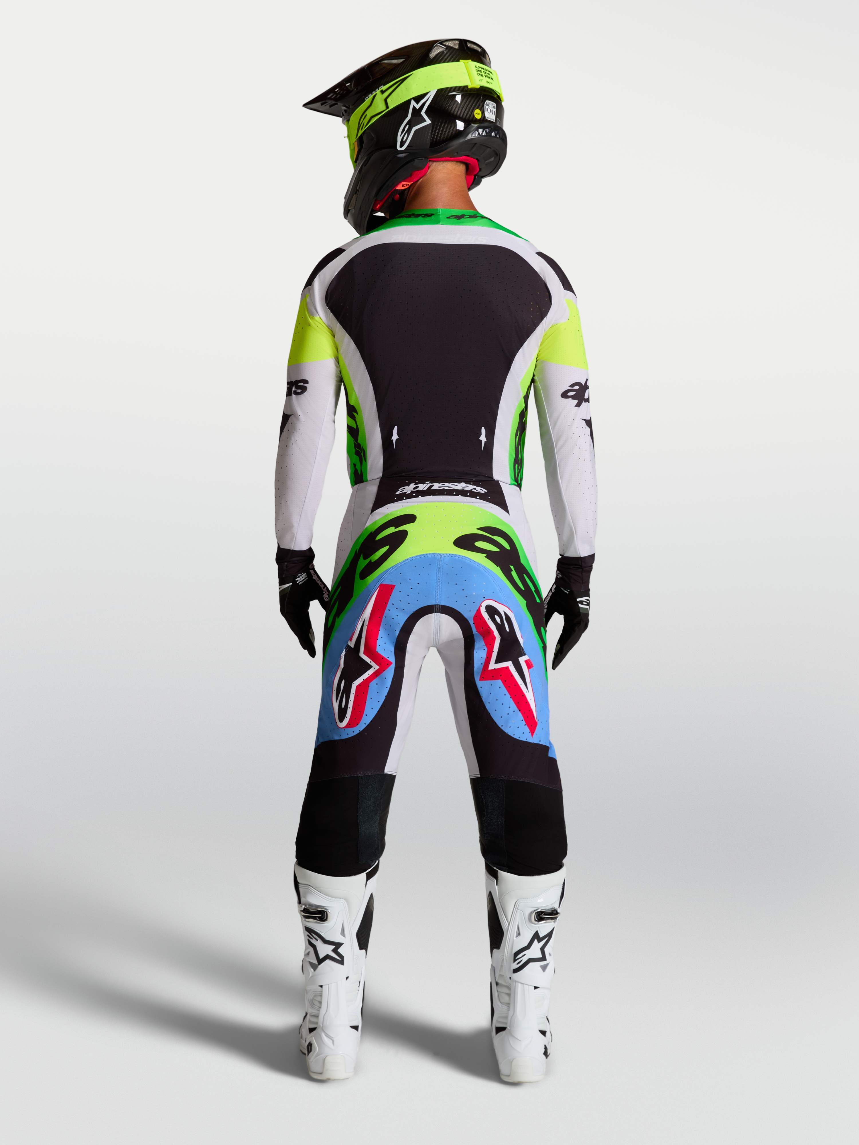 Alpinestars Pantaloni Supertech Dyna, pantaloni motocross lilla e verde fluo, vista posteriore su pilota in kit da gara.