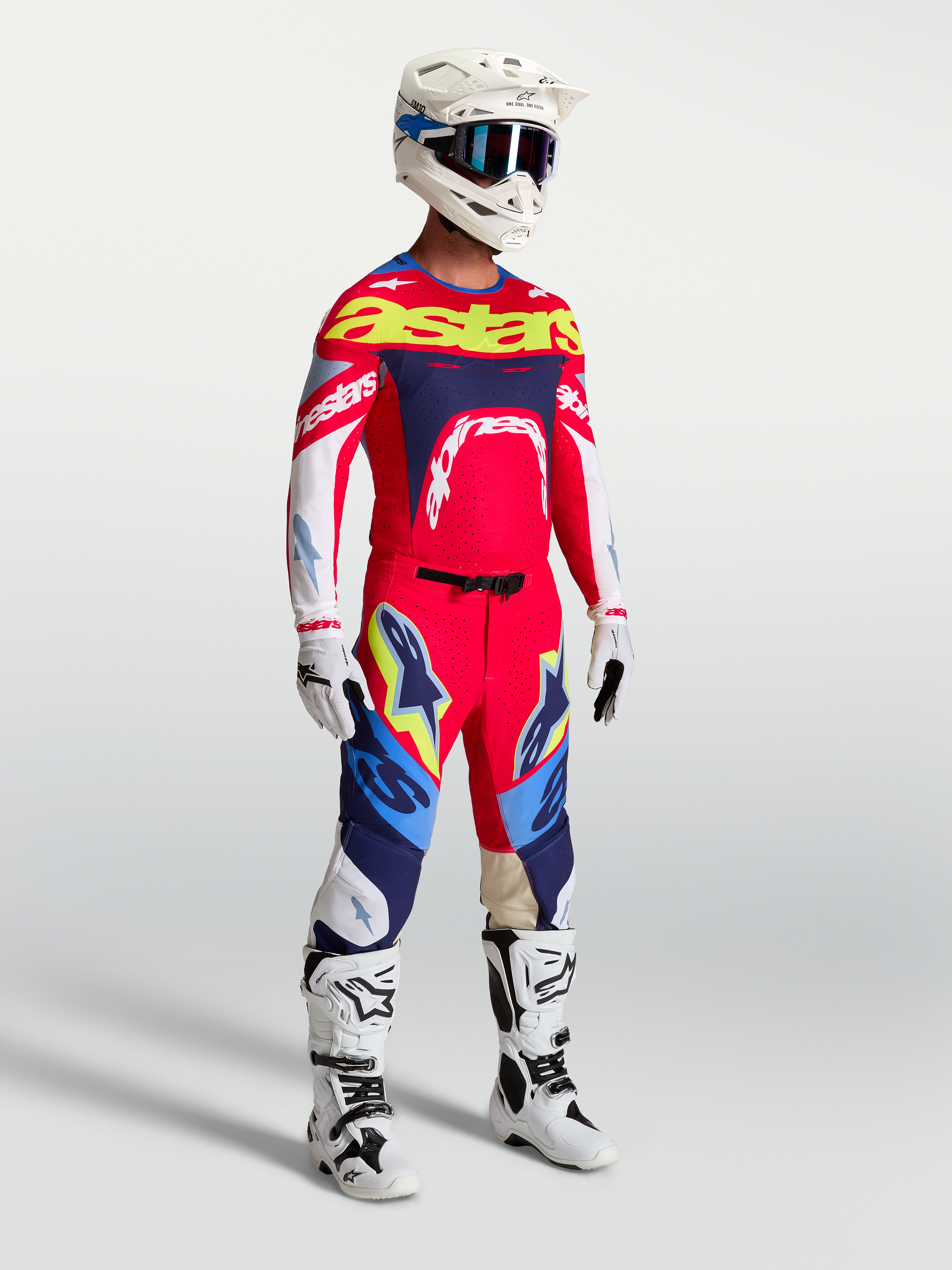 Alpinestars Pantaloni Supertech Dyna, completo motocross da uomo rosso e blu con maglia racing e stivali bianchi.