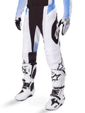 Alpinestars 2025 Techstar Melt Pants, pantaloni da motocross, bianco e nero con accenti blu, con perforazioni laser per la ventilazione e costruzione del ginocchio Babel, indossati con stivali e guanti da motocross bianchi abbinati, design atletico per gare off-road