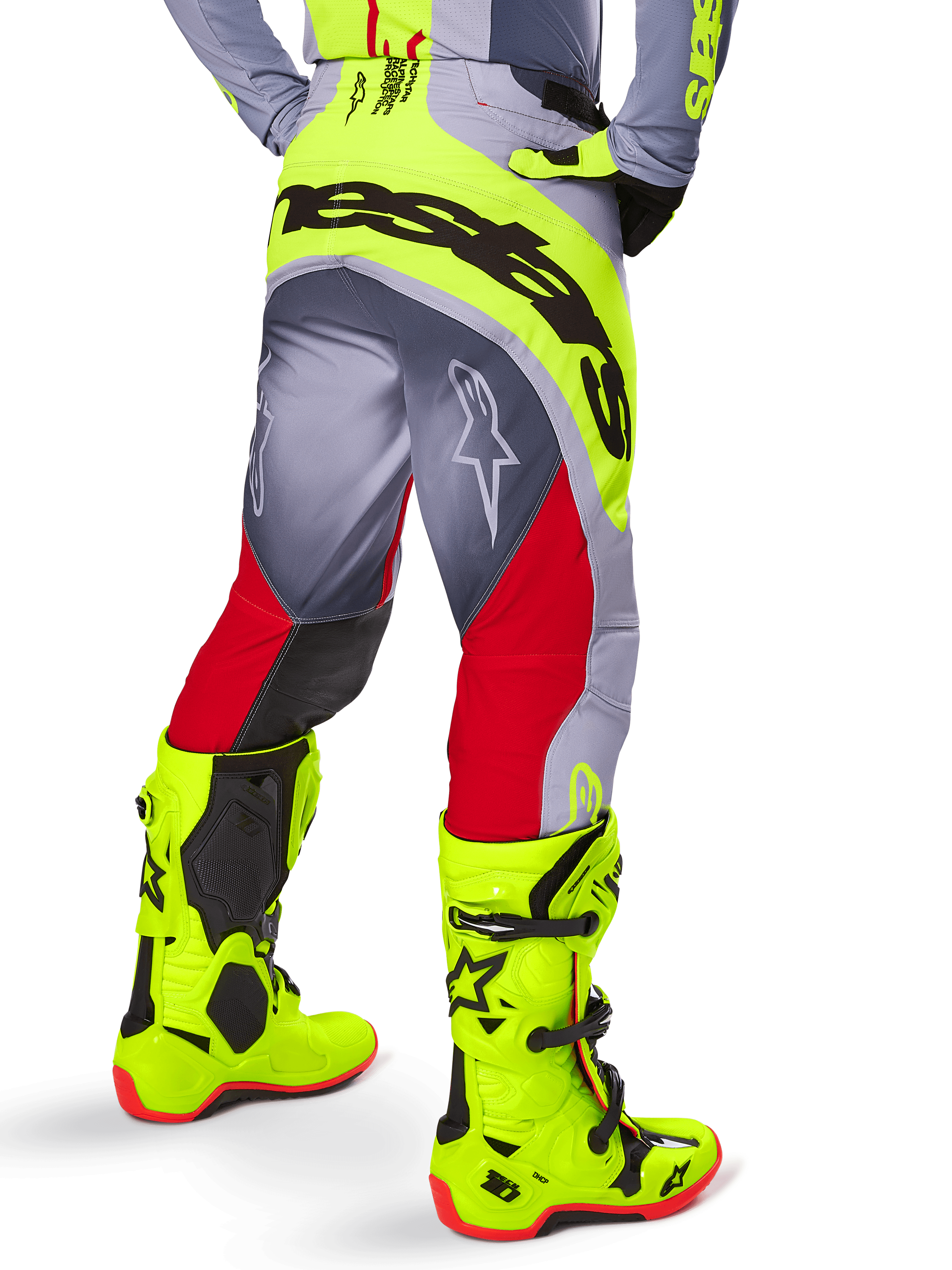Alpinestars 2025 Techstar Melt Pants, pantaloni da motocross, rosso acceso e grigio con dettagli giallo neon, vista posteriore con grande logo nero sulla seduta, indossati con stivali giallo brillante e maglia grigia, vestibilità race per competizioni fuoristrada.