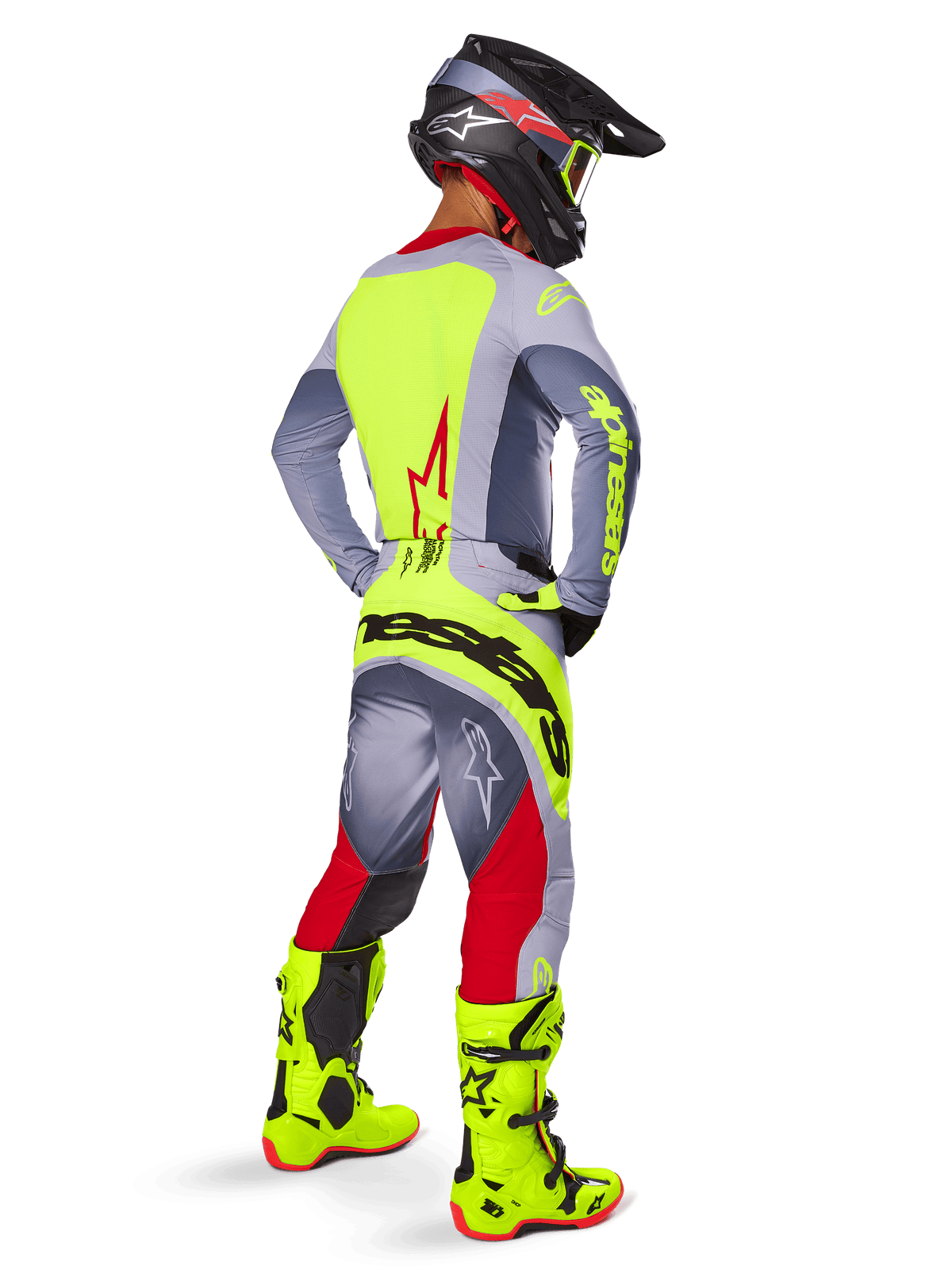 Pilota di motocross con Set Gear Alpinestars Techstar Melt 2025, visto dal retro, maglia grigia con pannello posteriore giallo neon e logo rosso, pantaloni grigi e rossi con marchio 'Alpinestars' giallo neon sulla seduta, stivali da motocross giallo neon e casco coordinato