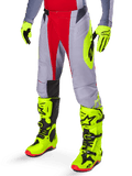 Alpinestars 2025 Techstar Melt Pants, pantaloni da motocross, rosso acceso e grigio, con grafiche laterali giallo neon e pannelli neri sulle ginocchia, abbinati a stivali e guanti giallo neon coordinati, progettati per prestazioni off-road competitive