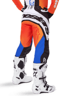 Alpinestars 2025 Techstar Melt Pants, pantaloni da motocross, arancione e blu, visti da dietro, con grande logo bianco sulla seduta, indossati con maglia arancione coordinata e stivali Tech 10 bianchi, abbigliamento da gara fuoristrada resistente
